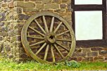Holzwagenrad vor Steinwand und Fachwerk