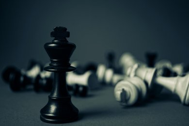 Die schwarze Schachfigur-Königin hat alle anderen Figuren besiegt und steht im Vordergrund