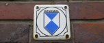 Schild mit Denkmalemblem in blau-weiß auf Mauersteinen