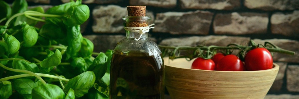 Arrangement mit Balsamicoflasche, Tomaten in Holzschüssel und Basilikum