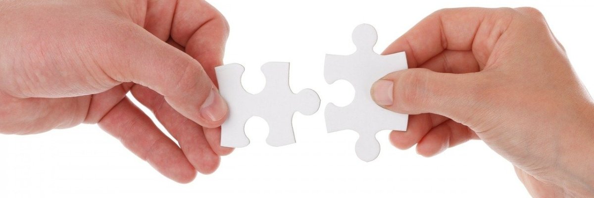 zwei Hände fügen zwei weiße Puzzleteile zusammen