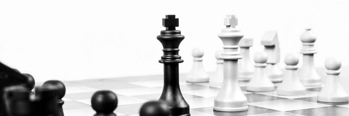 Schachfiguren in schwarz und weiß stehen sich auf einem Schachbrett gegenüber